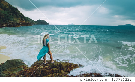Woman meditates, relaxes on a rock reef hill in stormy morning rain cloudy sea. Concept feminine, relax, sexual health. Dark dramatic silhouette view Woman meditates, relaxes on a rock reef hill in stormy morning rain cloudy sea. Concept feminine, relax, sexual health. Dark dramatic silhouette view 127755223