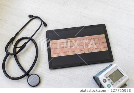 Table with phonendoscope, sphygmomanometer and myocardial infarction cardiogram on the tablet Table with phonendoscope, sphygmomanometer and myocardial infarction cardiogram on the tablet 127755958