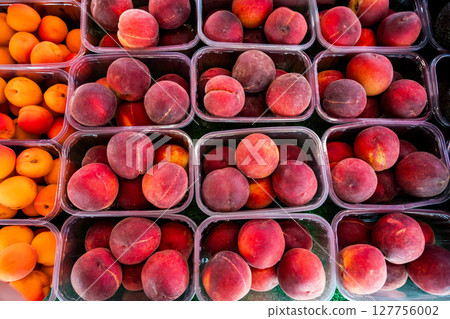 Peaches fruits in plastic containers, outdoor market display stall, top view 127756002