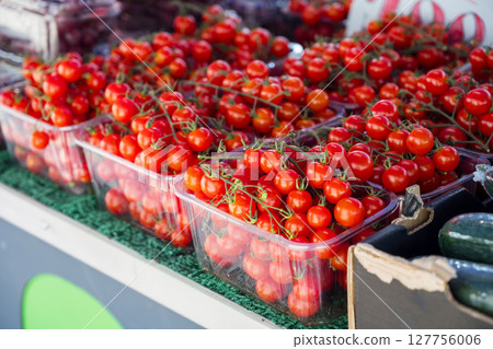 Red cherry tomatoes in plastic trays, outdoor farm market 127756006
