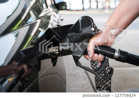 Man driver hand refilling the car with fuel at the gas petrol station.  127756024