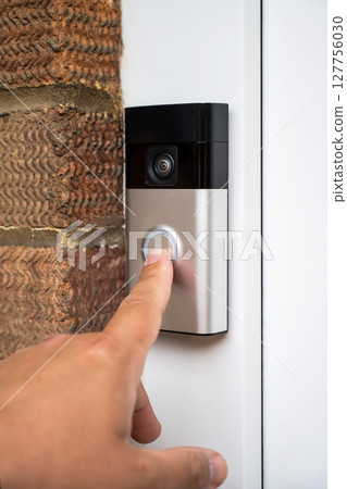 Close-up of man's hand pressing the button of a doorbell on a brick wall 127756030