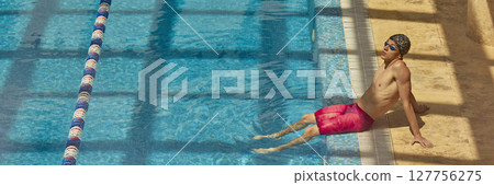 Man in red swim shorts relaxing poolside under sunlight Man in red swim shorts relaxing poolside under sunlight 127756275
