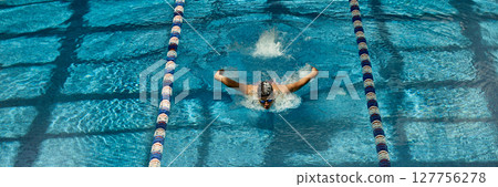 Swimmer executing butterfly stroke in competitive swimming pool lane 127756278