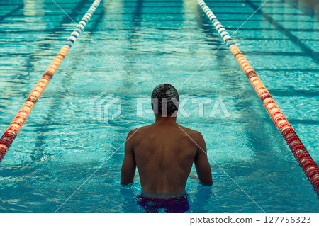 Swimmer preparing for race in indoor pool with clear lanes and blue water 127756323