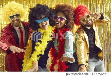Group of happy people in boas and curly wigs dancing and having fun at disco party 127756540