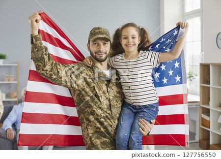 Portrait of a military father and his daughter holding an American flag while standing at home. Portrait of a military father and his daughter holding an American flag while standing at home. 127756550