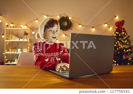 Surprised boy using laptop, choosing presents online, playing games or reading email from Santa Surprised boy using laptop, choosing presents online, playing games or reading email from Santa 127756591