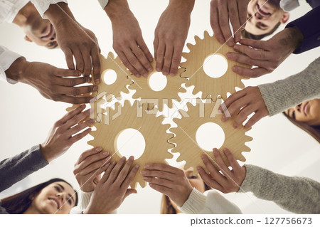 Business team joining gears as metaphor for teamwork and finding creative solutions Business team joining gears as metaphor for teamwork and finding creative solutions 127756673
