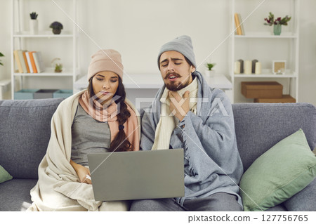 Couple, suffering from flu, sitting on couch and having medical consultation via video call 127756765