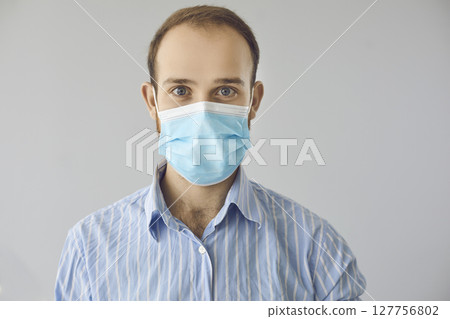 Portrait of happy friendly office worker in blue medical face mask looking at camera 127756802