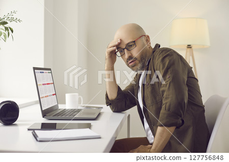 Busy man overwhelmed with work using calendar on laptop and planning his schedule Busy man overwhelmed with work using calendar on laptop and planning his schedule 127756848