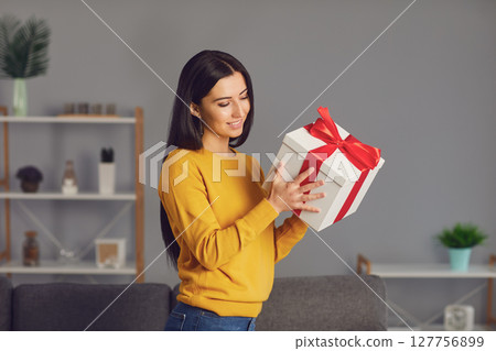 Charming woman holding present box with bow 127756899