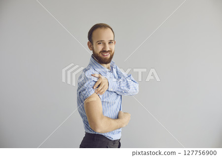 Portrait of happy young office worker smiling and showing his arm after getting vaccine 127756900