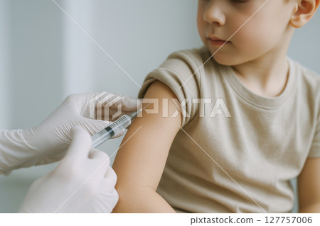 Child receives vaccine injection in upper arm from healthcare professional wearing white gloves, highlighting importance of vaccination for child health and safety Child receives vaccine injection in upper arm from healthcare professional wearing white gloves, highlighting importance of vaccination for child health and safety 127757006
