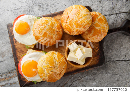 Chinese snack sandwiches made of bolo bao bun with fried egg, butter, tomatoes, cheese close-up on wooden board. horizontal top view Chinese snack sandwiches made of bolo bao bun with fried egg, butter, tomatoes, cheese close-up on wooden board. horizontal top view 127757020