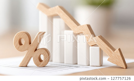 Declining interest rate concept with wooden percentage symbol and downward arrow on white bar chart showing financial risk and potential bankruptcy in economic market trends 127757126