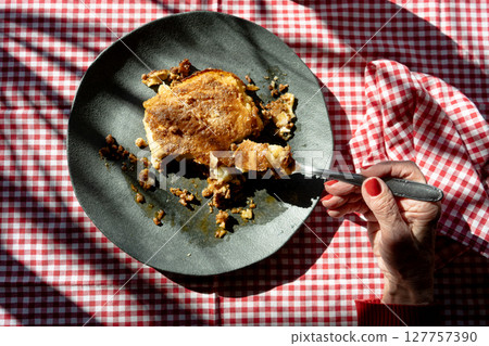 Woman's Hand cutting a homemade shepherd's pie freshly baked. Woman's Hand cutting a homemade shepherd's pie freshly baked. 127757390