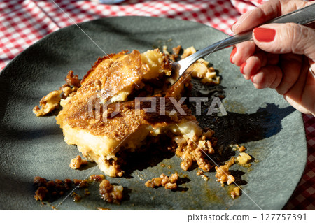 Woman's Hand cutting a homemade shepherd's pie freshly baked. Woman's Hand cutting a homemade shepherd's pie freshly baked. 127757391