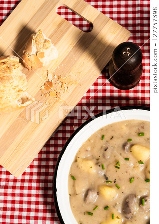 Creamy potato soup with mushrooms and chives served on checkered tablecloth with bread Creamy potato soup with mushrooms and chives served on checkered tablecloth with bread 127757398