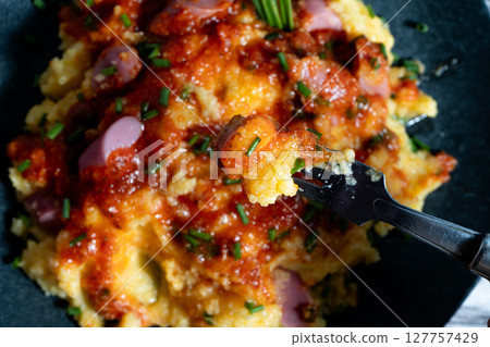 Fork lifting portion of creamy polenta with sausage and tomato sauce Fork lifting portion of creamy polenta with sausage and tomato sauce 127757429