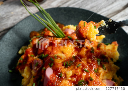 Fork lifting delicious bite of creamy polenta with sausage and tomato sauce Fork lifting delicious bite of creamy polenta with sausage and tomato sauce 127757430