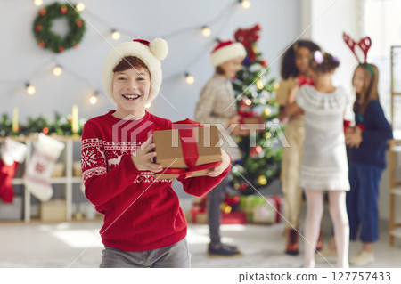 Portrait of a happy boy with a Christmas present in his hands in a room with Christmas decorations. Portrait of a happy boy with a Christmas present in his hands in a room with Christmas decorations. 127757433