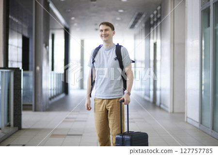 A male traveler walking down the aisle pulling a suitcase A male traveler walking down the aisle pulling a suitcase 127757785