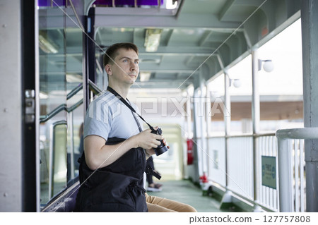 一名男性旅客在渡輪舷梯上拿著相機 127757808