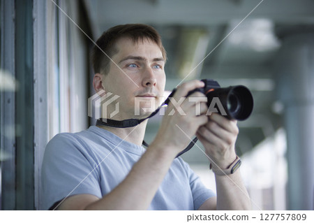 Male traveler holding a camera on the ferry's gangway Male traveler holding a camera on the ferry's gangway 127757809