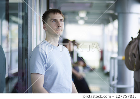 A man traveling alone stands along the ferry's passageway 127757813