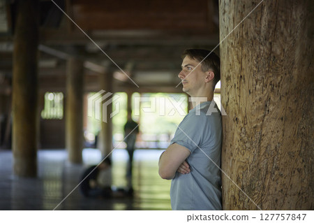 Portrait of a male traveler leaning against a pillar 127757847