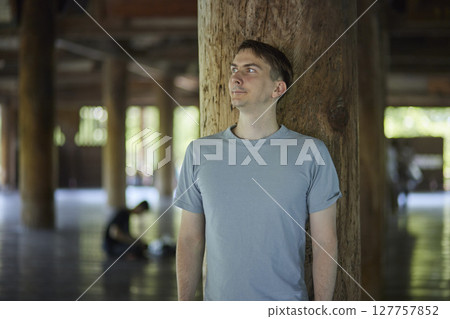 Portrait of a male traveler leaning against a pillar 127757852