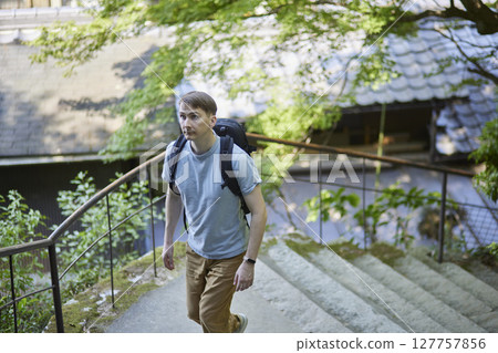 一名男子背著背包，沿著被大自然環繞的小路行走 127757856