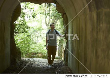 Backpackers exploring a forest tunnel Backpackers exploring a forest tunnel 127757914