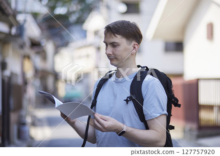 Backpackers checking tourist guides on street corners 127757920