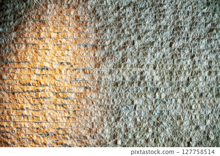 The surface of a stone wall reflecting orange light 127758514