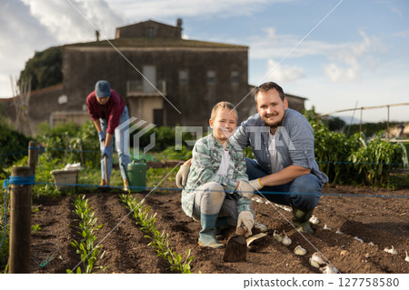Man and his son planting seeds on a farm Man and his son planting seeds on a farm 127758580