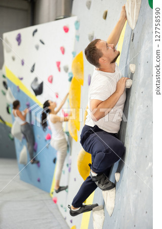 Young man practicing rock climbing on climbing wall Young man practicing rock climbing on climbing wall 127758590