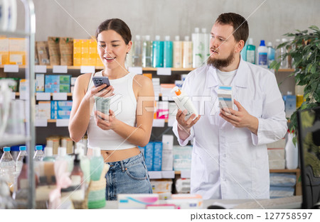 Woman buyer scans cream qr code with man pharmacist Woman buyer scans cream qr code with man pharmacist 127758597