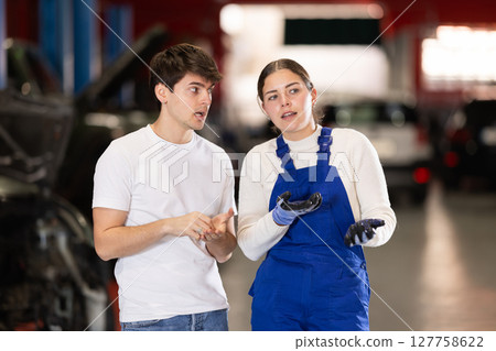 guy consults with a car service worker 127758622