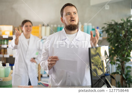 Confused male pharmacist employee during argument with boss Confused male pharmacist employee during argument with boss 127758646