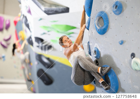 Young woman practicing rock climbing on climbing wall Young woman practicing rock climbing on climbing wall 127758648