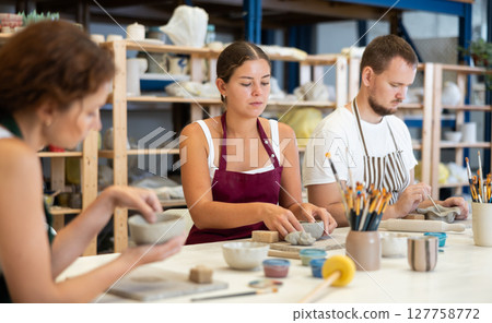 Three students in pottery workshop learn to create homemade plates and other utensils 127758772