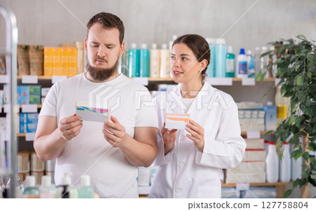 Man chooses pills in modern pharmacy. Female pharmacist helps with choosing medicine Man chooses pills in modern pharmacy. Female pharmacist helps with choosing medicine 127758804