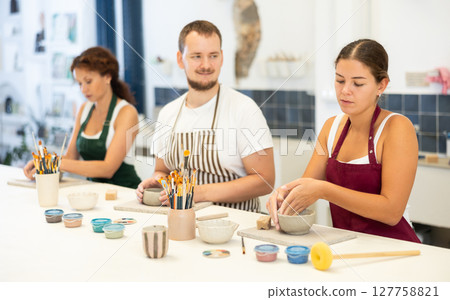 Three pottery workshop workers sculpt from raw clay 127758821
