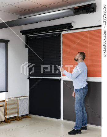 Man Demonstrating Motorized Blinds in Sun Protection Showroom Man Demonstrating Motorized Blinds in Sun Protection Showroom 127759156