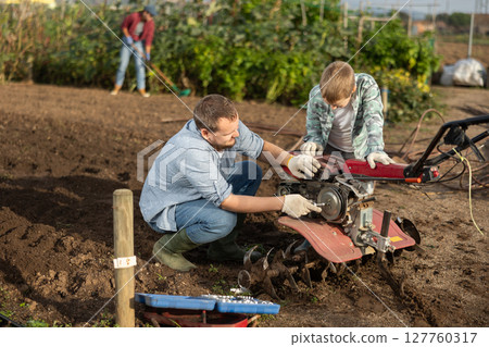 Man and his son are repairing garden equipment Man and his son are repairing garden equipment 127760317