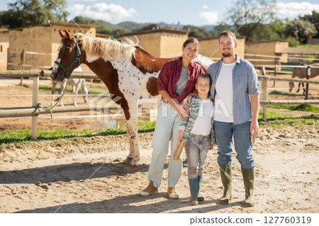 Father, mother and son riding horse together at small horse farm 127760319