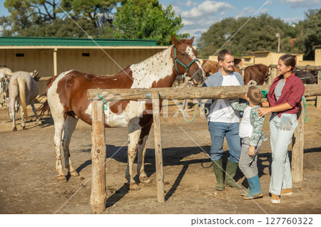 Man, woman and boy with horse at hitching post 127760322